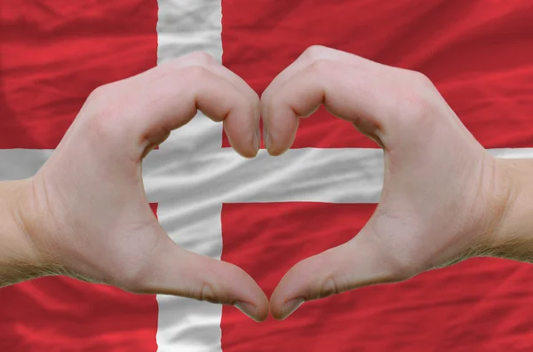 Srdce a lásku gestem ukázal rukou nad vlajkou Dánska zpět — Stock fotografie