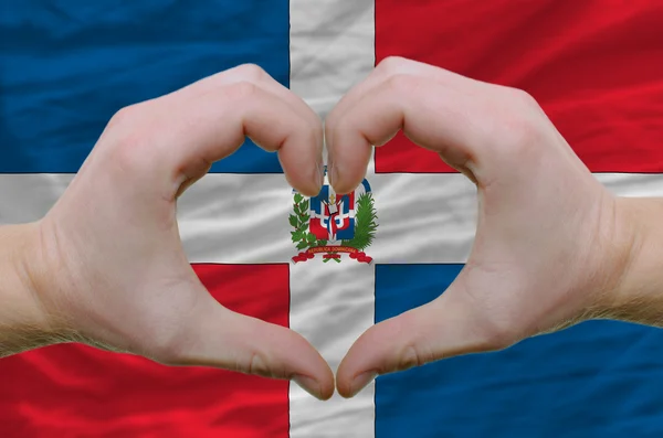 Inima și gestul de dragoste arătat de mâinile deasupra steagului dominican — Fotografie, imagine de stoc