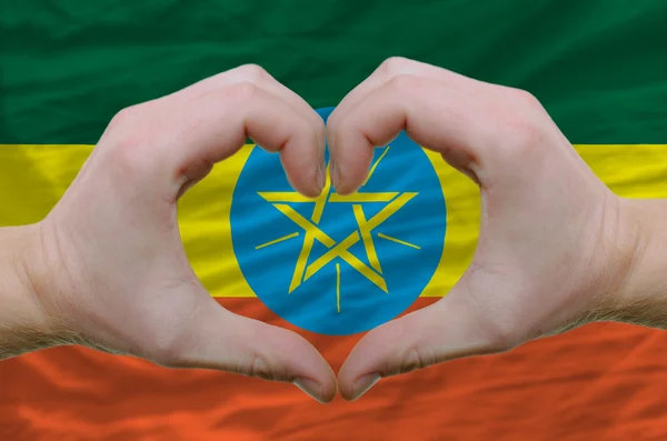 Srdce a lásku gestem ukázal rukou nad vlajka Etiopie bac — Stock fotografie