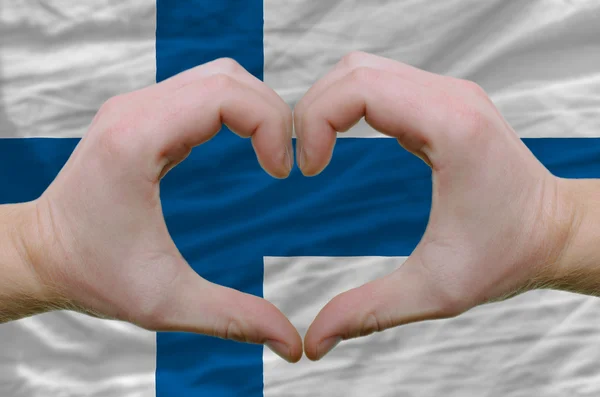 心和爱的姿态显示了由手对国旗的芬兰背 — 图库照片