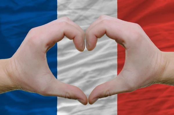 Srdce a lásku gestem ukázal rukou nad vlajkou Francie backg — Stock fotografie