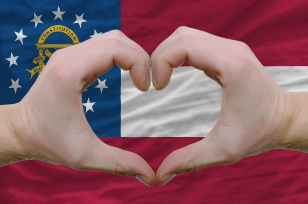 El corazón y el gesto de amor mostrados por las manos sobre la bandera de Georgia espalda — Foto de Stock