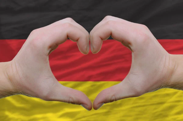 El corazón y el gesto de amor mostrados por las manos sobre la bandera de Alemania espalda —  Fotos de Stock