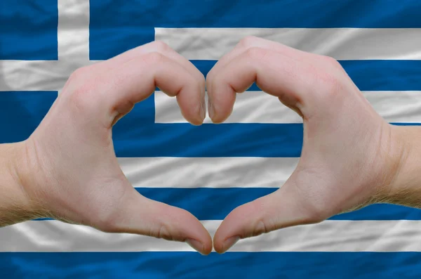 ギリシャの背景に隠れての旗上の手によって示した心と愛のジェスチャー — ストック写真