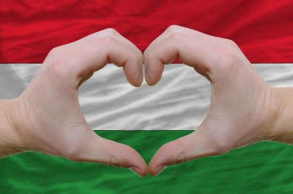 Coração e gesto de amor mostrados por mãos sobre a bandeira de costas húngaras — Fotografia de Stock
