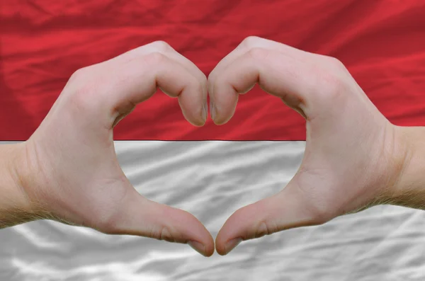 El corazón y el gesto de amor mostrados por las manos sobre la bandera de indonesia ba — Foto de Stock