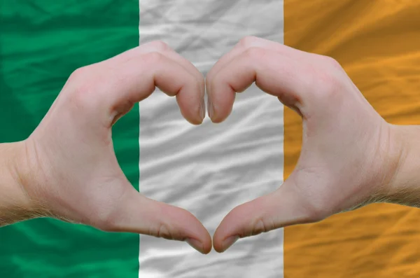 El corazón y el gesto de amor mostrado por las manos sobre la bandera de Irlanda espalda — Foto de Stock