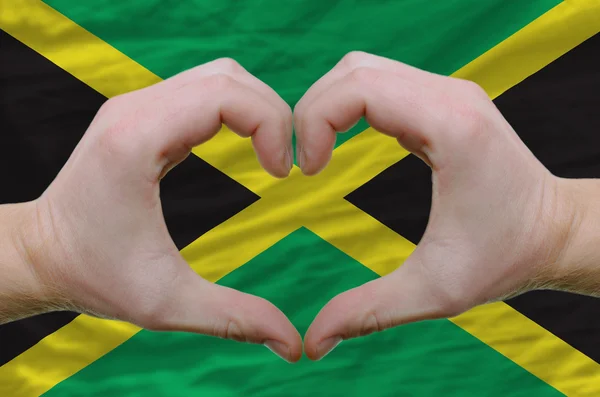 Жест любви и сердца, показываемый руками над флагом Ямайки — стоковое фото
