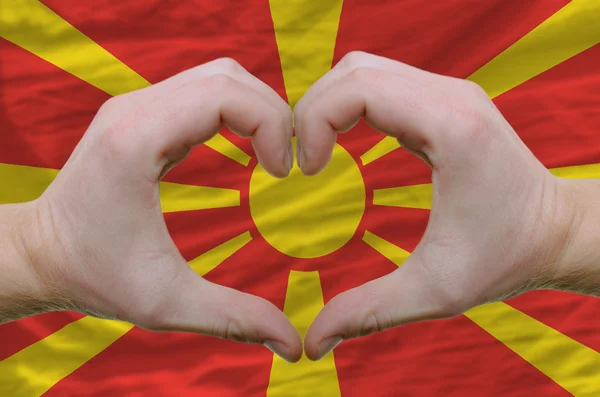 Srdce a lásku gestem ukázal rukou nad vlajka Makedonie ba — Stock fotografie
