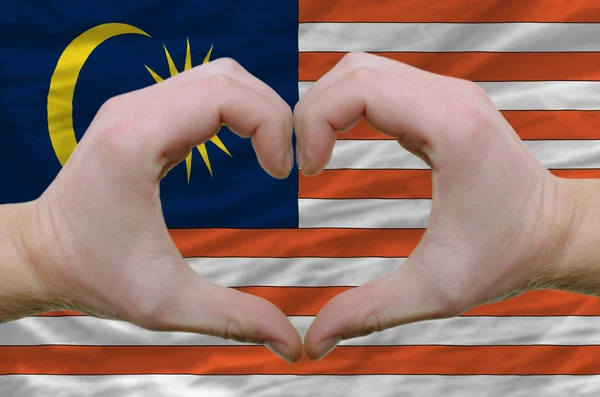 Srdce a lásku gestem ukázal rukou nad vlajkou Malajsie bac — Stock fotografie