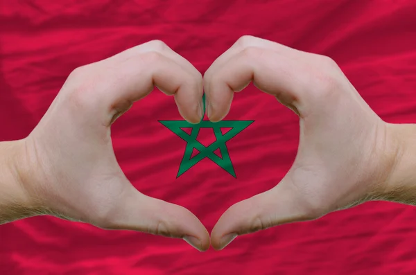 El corazón y el gesto de amor mostrados por las manos sobre la bandera de Marruecos espalda — Foto de Stock