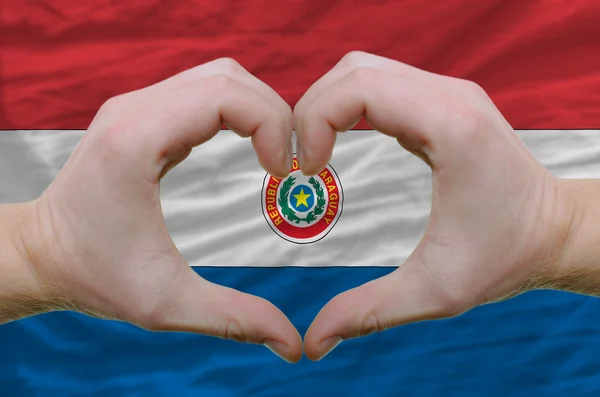 El corazón y el gesto de amor mostrados por las manos sobre la bandera de paraguay bac —  Fotos de Stock