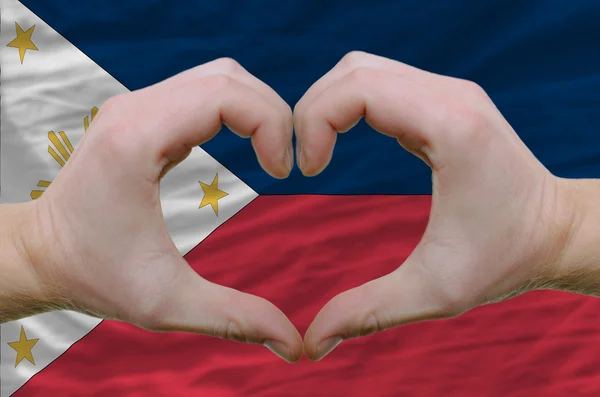 El corazón y el gesto de amor mostrados por las manos sobre la bandera de Filipinas —  Fotos de Stock