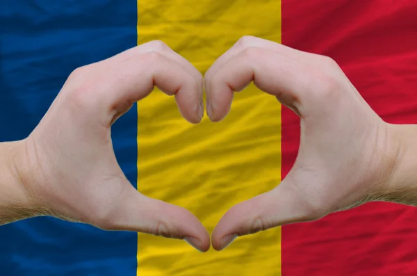 Srdce a lásku gestem ukázal rukou nad vlajka Rumunska zpět — Stock fotografie