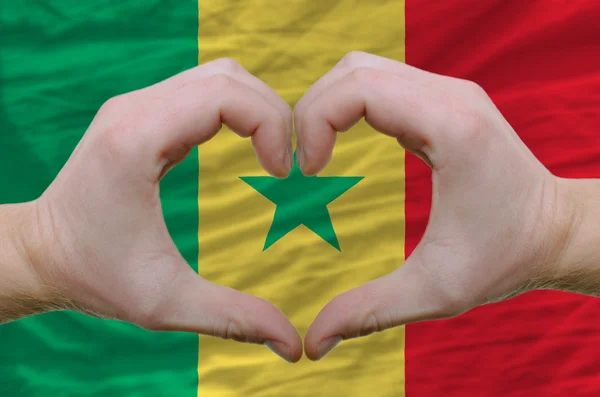 Жест любви и сердца, показываемый руками над флагом Сенегала — стоковое фото