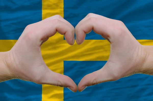Cuore e amore gesto mostrato dalle mani sopra la bandiera del dorso svedese — Foto Stock
