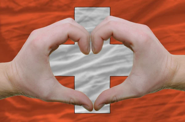 Жест любви и сердца, показываемый руками над флагом Швитцерлана — стоковое фото