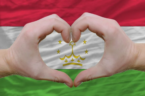 Srdce a lásku gestem ukázal rukou nad Vlajka Tádžikistánu b — Stock fotografie