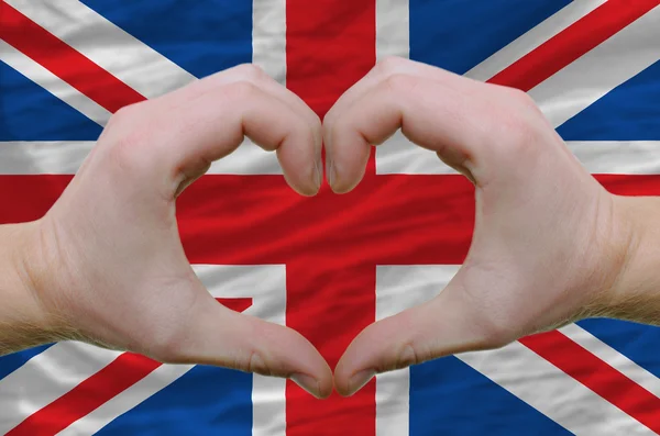 Srdce a lásku gestem ukázal rukou nad vlajkou Spojeného království poza — Stock fotografie