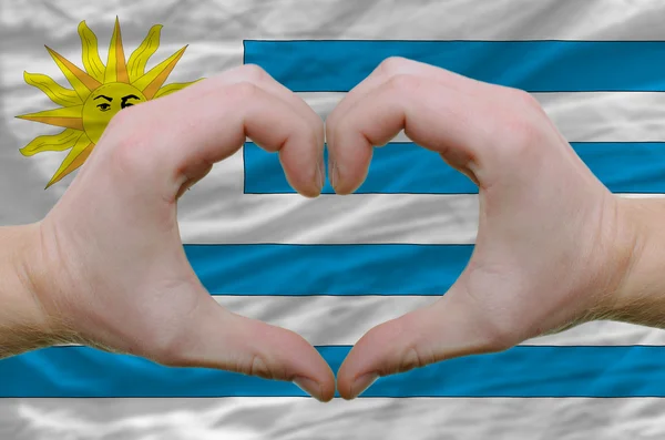 El corazón y el gesto de amor mostrados por las manos sobre la bandera de uruguay espalda —  Fotos de Stock