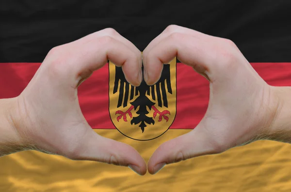 Cœur et geste d'amour montré par les mains sur le drapeau de l'Allemagne dos — Photo