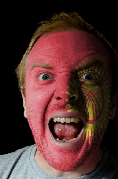 Face of crazy angry man painted in colors of kyrghyzstan flag — Stock Photo, Image