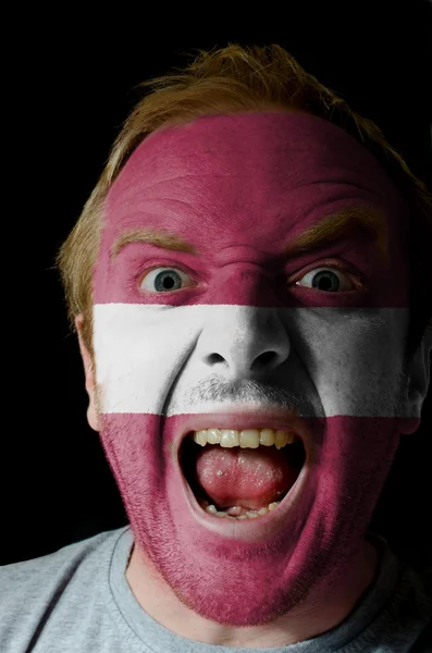 Visage de fou homme en colère peint dans les couleurs du drapeau latvia — Photo