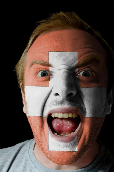 Gesicht des verrückten wütenden Mannes in den Farben der Schweizer Flagge gemalt — Stockfoto