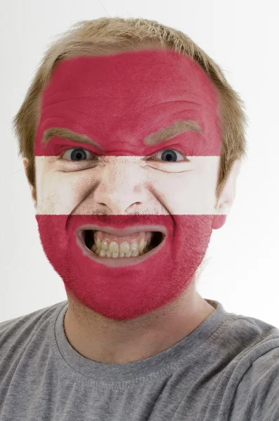 Face of crazy angry man painted in colors of latvia flag — Stock Photo, Image