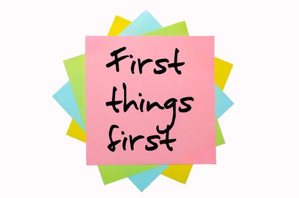 Provérbio "Primeiras coisas primeiro" escrito em um monte de notas pegajosas — Fotografia de Stock