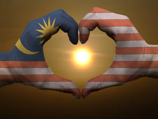 Жест любви и сердца руками, раскрашенными в малайзийский флаг во время — стоковое фото