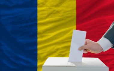 Man voting on elections in romania in front of flag clipart