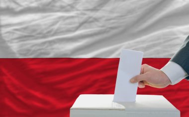 Man voting on elections in poland in front of flag clipart