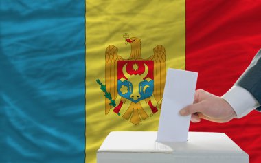 Man voting on elections in moldova in front of flag clipart