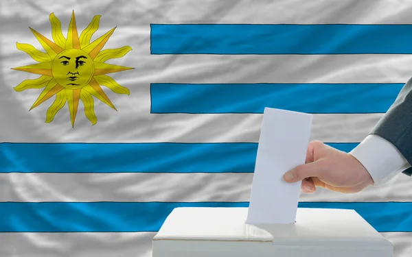 Homem votando nas eleições em uruguai em frente à bandeira — Fotografia de Stock