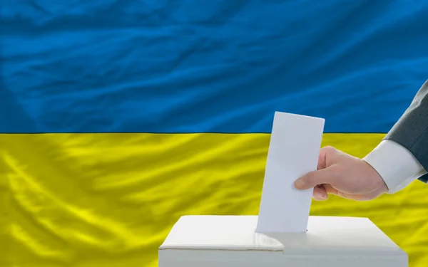 Homem votando nas eleições na Ucrânia em frente à bandeira — Fotografia de Stock