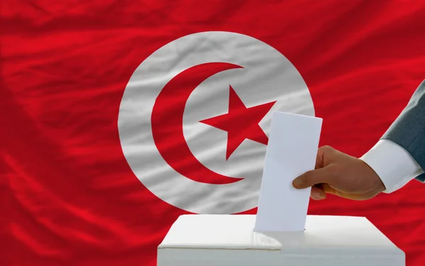 Homem votando nas eleições na tunisia em frente à bandeira — Fotografia de Stock