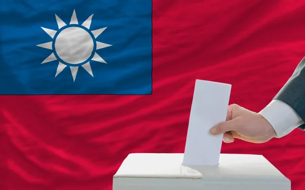Мужчина голосует на выборах в Тайване перед флагом — стоковое фото
