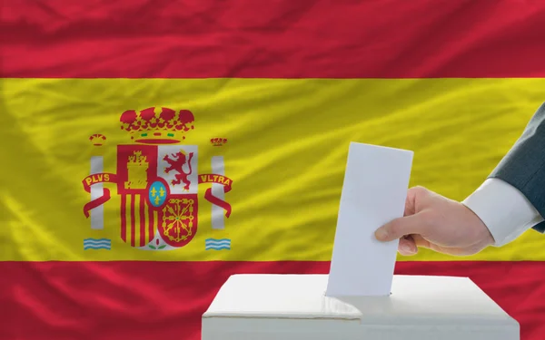 Мужчина голосует на выборах в Испании перед флагом — стоковое фото