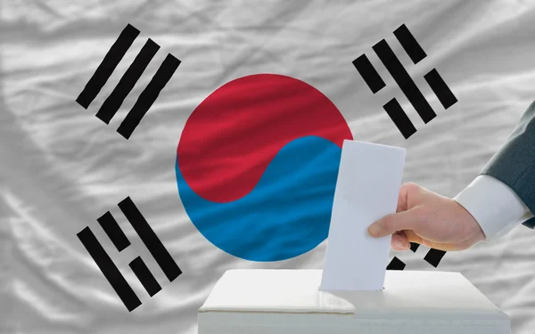 Мужчина голосует на выборах в Южной Корее перед флагом — стоковое фото