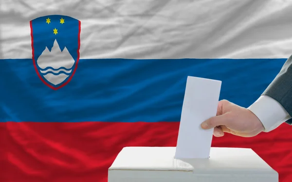 Άνθρωπος ψηφοφορία στις εκλογές στη Σλοβενία, μπροστά από την σημαία — Φωτογραφία Αρχείου
