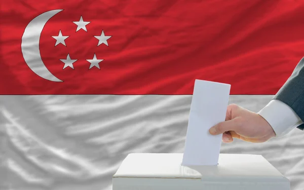Homem votando nas eleições em Cingapura em frente à bandeira — Fotografia de Stock