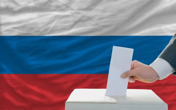 Homem votando nas eleições na Rússia em frente à bandeira — Fotografia de Stock
