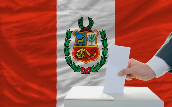 Мужчина голосует на выборах в Перу перед флагом — стоковое фото