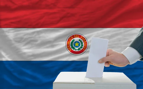 Homem votando nas eleições no paraguai em frente à bandeira — Fotografia de Stock
