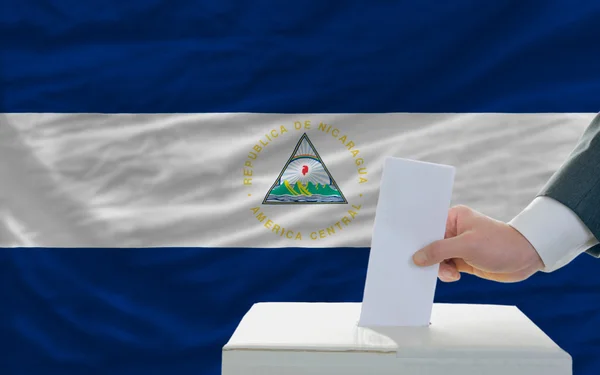 Homem votando em eleições na nicarágua na frente da bandeira — Fotografia de Stock