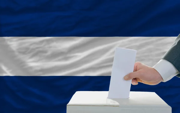 Homem votando em eleições na nicarágua na frente da bandeira — Fotografia de Stock