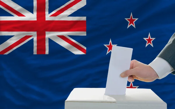 Мужчина голосует на выборах в Новой Зеландии перед флагом — стоковое фото