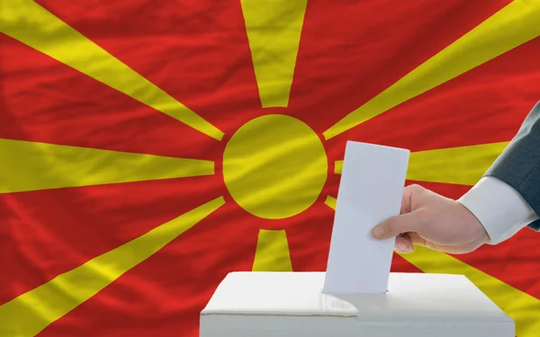 Muž hlasování o volbách v Makedonii před vlajky — Stock fotografie
