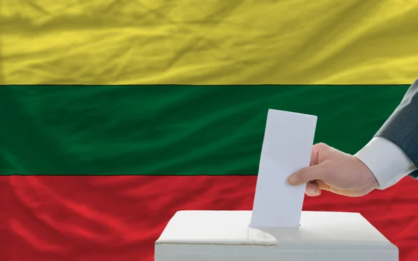 Człowiek głosowania w wyborach na Litwie przed flagą — Zdjęcie stockowe